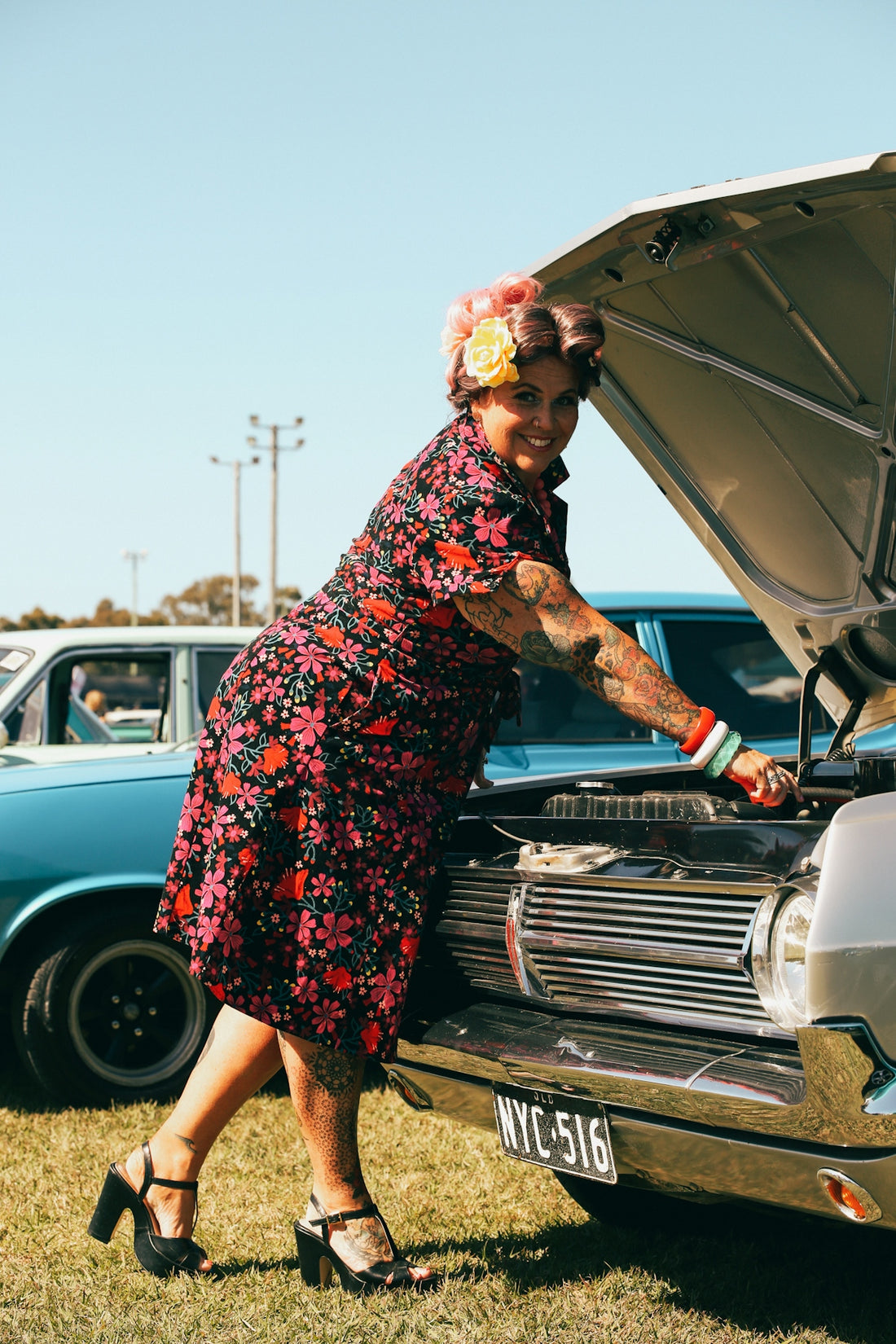 woman in black and red floral dress leaning on white car during daytime